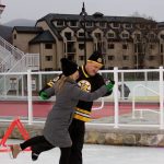Two people glide across the ice together, ballroom dance style.