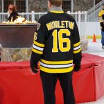 Individual wearing a “Middleton” Bruins jersey stands on the ice rink with their back to the camera.