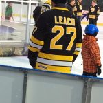 Individual with back towards camera skates on ice rink sporting “Leach 27” Bruins jersey.