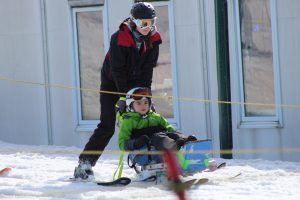 PAC volunteer pushes child in Bi-Ski