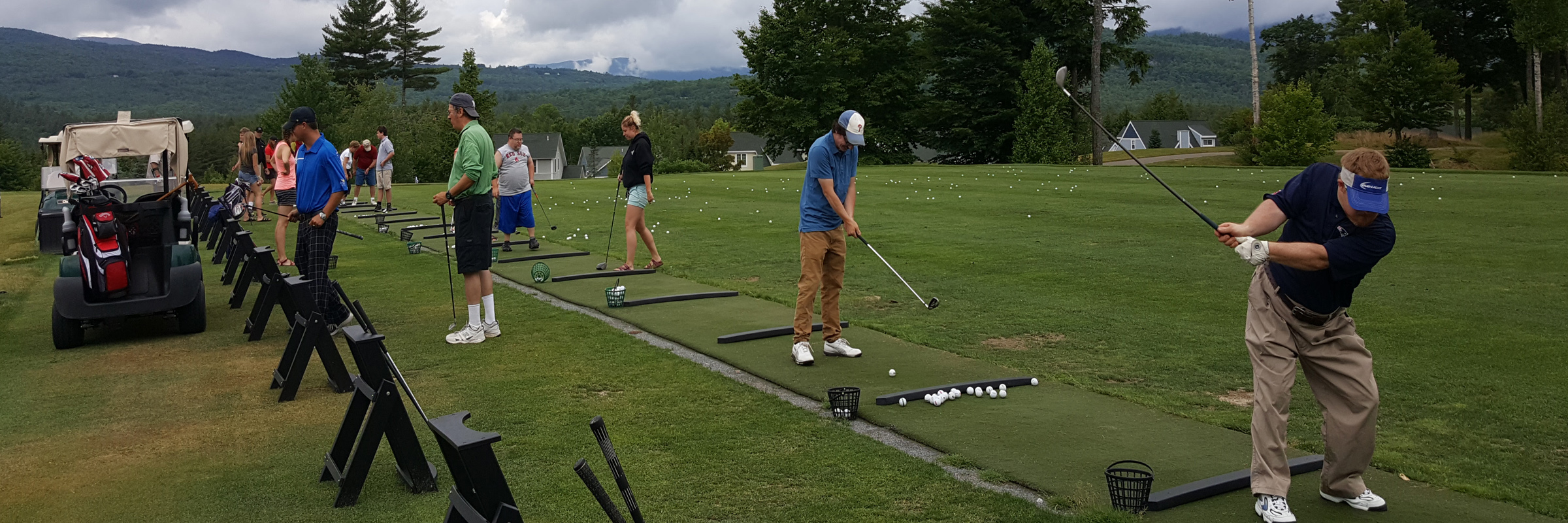 A group of individuals practicing on the driving range at the golf course.